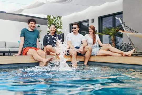 Two men and two women sitting by a pool
